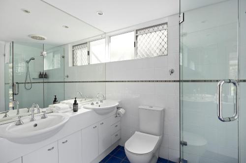 a bathroom with a toilet and two sinks and a shower at Noosa Haven Apt 6 Riverside Retreat in Noosaville