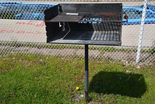 a barbecue grill sitting in the grass next to a fence at Harmony Inn in Goderich