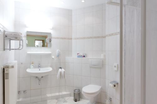 a white bathroom with a toilet and a sink at Parkhotel del Mar in Sassnitz