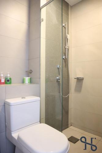 a bathroom with a toilet and a glass shower at Homesuite' Home at The Loft in Kota Kinabalu