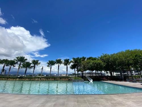 a swimming pool with palm trees and a blue sky at Homesuite' Home at The Loft in Kota Kinabalu