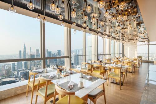 um restaurante com mesas e cadeiras e janelas grandes em Renaissance Shenzhen Bay Hotel em Shenzhen