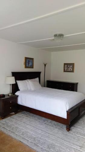 White Fang Motel في واوا: غرفة نوم بسرير كبير مع شراشف بيضاء ومصباح