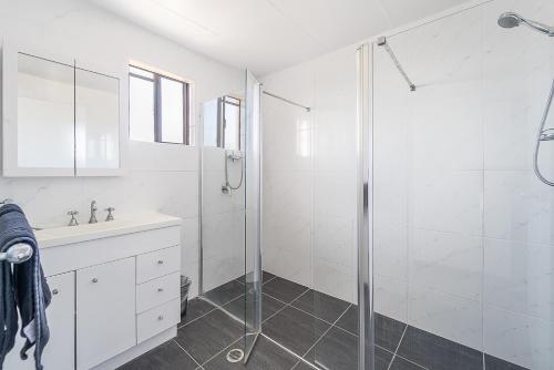 a white bathroom with a shower and a sink at Aaron Motel in Gladstone