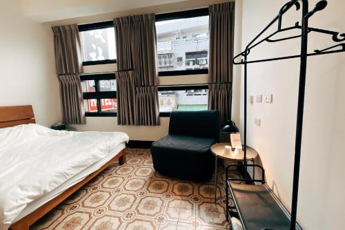 - une chambre avec un lit, une chaise et des fenêtres dans l'établissement 鴉埠客棧x南華大旅社, 
