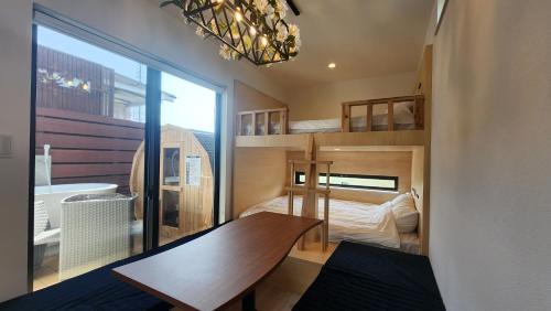 ein kleines Zimmer mit einem Holztisch und einem Schlafzimmer in der Unterkunft ZUMI TERRACE うちなーみやリゾート宮古島 in Miyako-jima