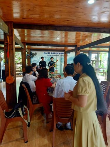 a group of people sitting around a table in a restaurant at Ba Be Green Homestay in Bak Kan