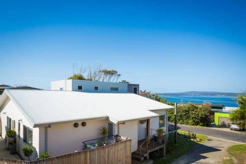 a white house with a fence and the ocean in the background at Sea Change and Studio on Tasman in Merimbula