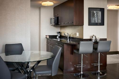 a small kitchen with a glass table and chairs at Sheraton Hamilton Hotel in Hamilton