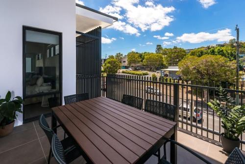 una terrazza con tavolo e sedie in legno sul balcone. di H6B - Round About Bulimba a Brisbane