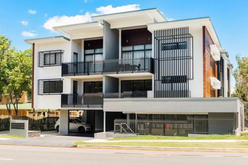 un edificio bianco con balconi neri su una strada di H6B - Round About Bulimba a Brisbane