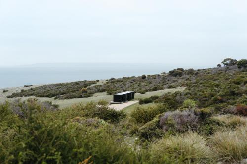 a black building on top of a hill with bushes at CABN Kangaroo Island in Penneshaw