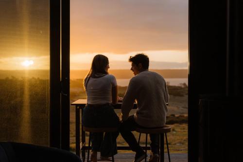 a man and woman sitting at a table in front of a window at CABN Kangaroo Island in Penneshaw