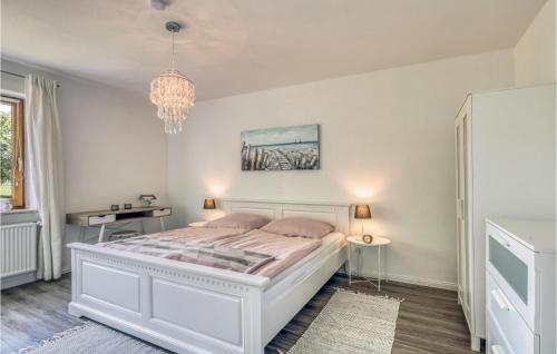 1 dormitorio con cama blanca y lámpara de araña en Amazing Apartment In Westerdeichstrich With Wifi, en Westerdeichstrich