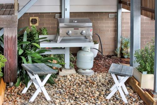 a grill and two benches in front of a house at Sea Change and Studio on Tasman in Merimbula