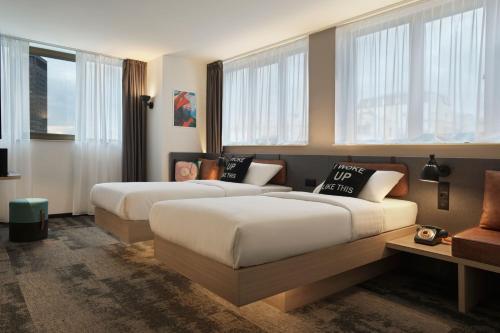 duas camas num quarto de hotel com janelas em Moxy Belgrade em Belgrado