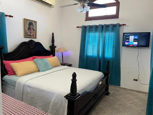 a bedroom with a bed with blue curtains and a television at Ocean Breeze Villa Carismar in Cabrera