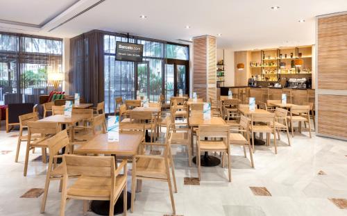 a restaurant with wooden tables and chairs and windows at Barceló Cabo de Gata in Retamar