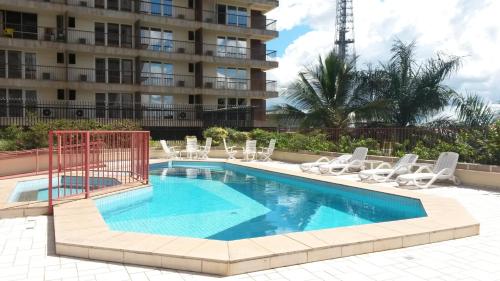 a swimming pool with chairs and a building at Grand Bittar Hotel in Brasília