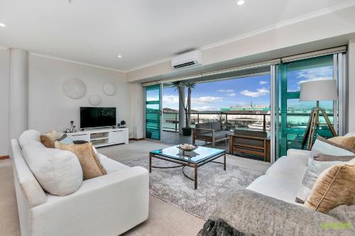 una sala de estar con muebles blancos y vistas al océano. en QV Upmarket Waterfront Apartment - 787, en Auckland