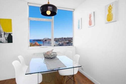 a dining room with a glass table and white chairs at S16S - Bondi Vistas in Sydney