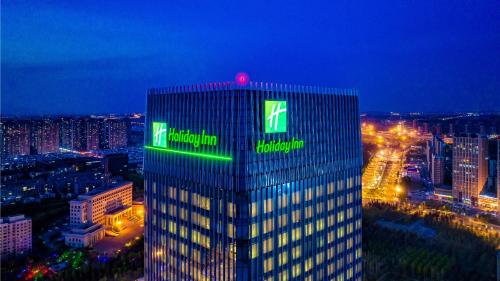 長春市にあるHoliday Inn Changchun Oriental Plaza, an IHG Hotelの緑の看板が立つ高層ビル