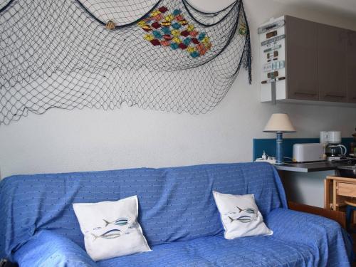 - un canapé bleu avec 2 oreillers blancs dans l'établissement Maison climatisée 3 pièces, 6 couchages près de la plage du Grazel à Gruissan - FR-1-229-851, à Gruissan