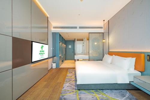 a bedroom with a bed and a flat screen tv at Holiday Inn Changchun Oriental Plaza, an IHG Hotel in Changchun