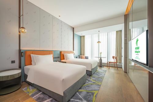 a hotel room with two beds and a flat screen tv at Holiday Inn Changchun Oriental Plaza by IHG in Changchun
