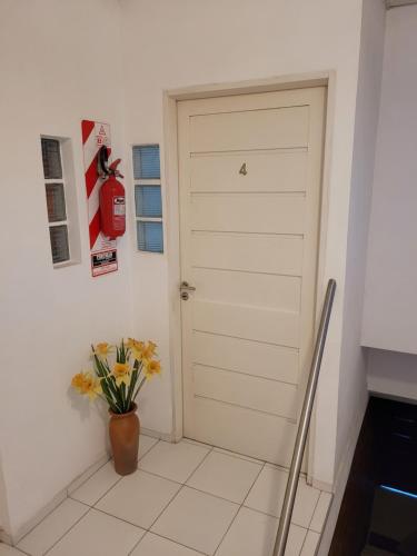 Una puerta blanca en una habitación con un jarrón de flores en Departamento - M I N I D O en Resistencia