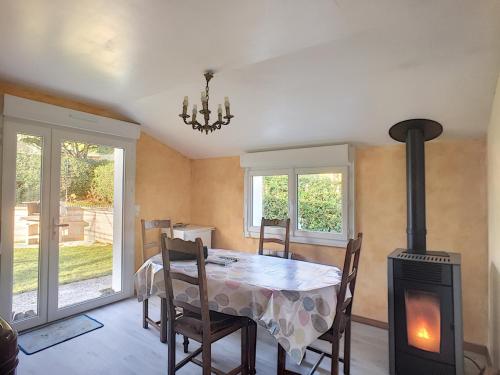 - une salle à manger avec une table et un poêle à bois dans l'établissement Maison paisible proche de la plage avec jardin et équipements complets - FR-1-361-491, à Carolles