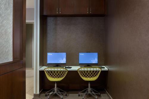 a desk with two monitors and two yellow chairs at SpringHill Suites by Marriott Bloomington in Bloomington