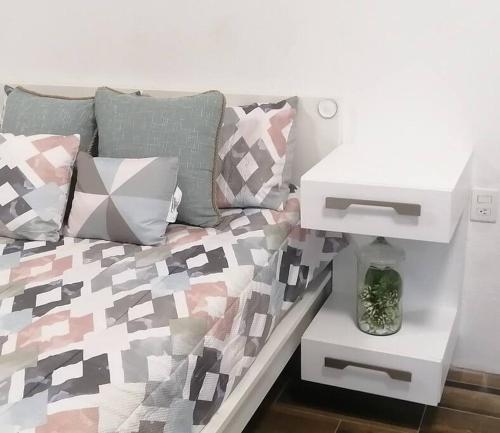 uma cama com almofadas coloridas e uma mesa branca em Disfruta de cómodo y bello departamento em Guadalajara
