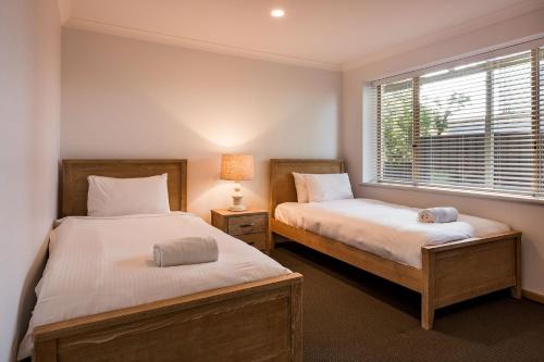 two beds in a room with a window at Heavenly Horizons in Dunsborough