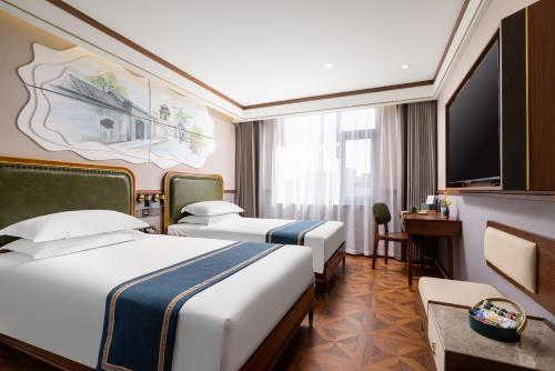 een hotelkamer met 2 bedden en een televisie bij Nostalgia Hotel S - Beijing National Convention Center in Beijing