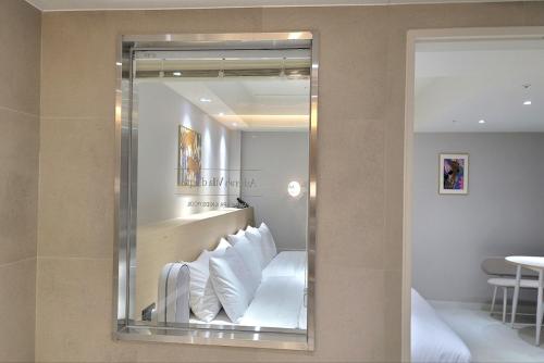 a mirror in a hotel room with white pillows at Asherah Villa d' aqua Hotel in Gimhae