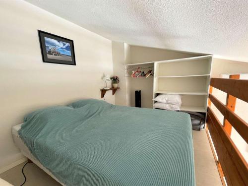 - une chambre avec un lit vert et une étagère dans l'établissement Studio mezzanine climatisé avec piscine, terrasse, parking privé et proche plage - Gruissan - FR-1-229-861, à Gruissan