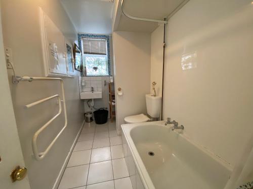 a white bathroom with a tub and a toilet at Beach front House in Wellington