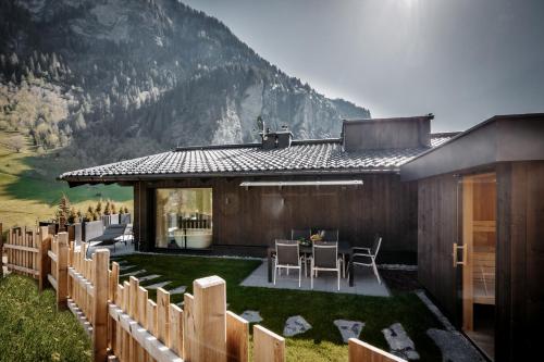 a house with a table and chairs in front of a mountain at ONKL XONNA Premium Alpin Chalets in Hüttschlag