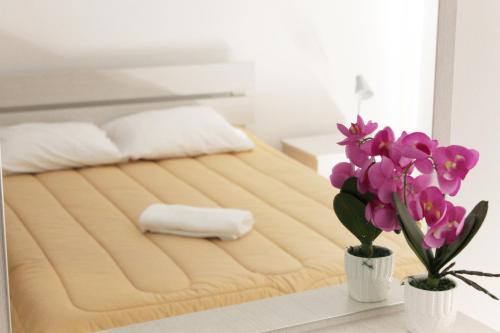 Una cama con dos jarrones con flores en una mesa en Tiffany City Apartments, en Lárnaca