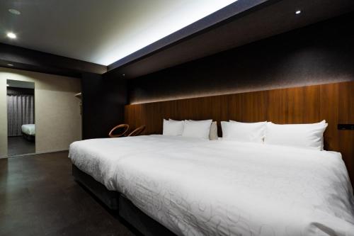 a bedroom with a large white bed with a wooden headboard at Randor Hotel Hiroshima Prestige in Hiroshima