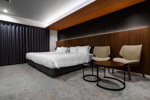 a hotel room with a bed and two chairs at Randor Hotel Hiroshima Prestige in Hiroshima