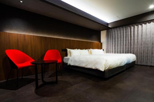 a bedroom with a bed and two red chairs at Randor Hotel Hiroshima Prestige in Hiroshima