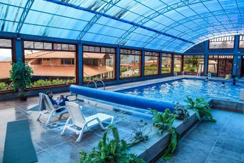 a man sitting in a chair in front of a swimming pool at Hostería San Clemente in Ibarra