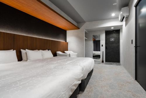 a bedroom with a large white bed with a wooden headboard at Randor Hotel Hiroshima Prestige in Hiroshima