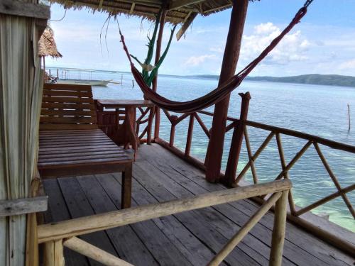 a porch with chairs and a hammock on the water at Daroyen Village in Kri