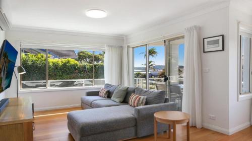 a living room with a couch and a large window at Moon Glow Views, Short Walk To Beach Accom Holidays in Terrigal