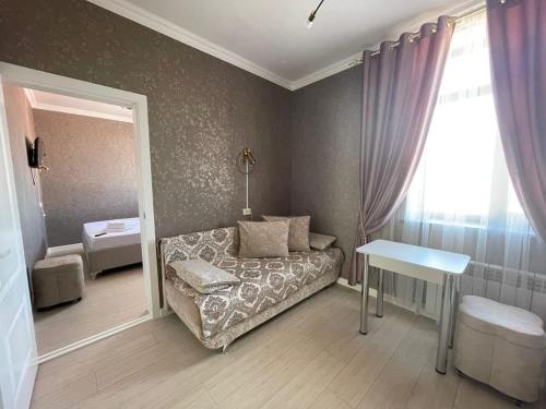 1 dormitorio con sofá, mesa y ventana en Keruen Deluxe, en Taraz