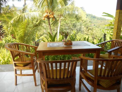 a wooden table and chairs on a patio with palm trees at Cegeng Lestari Guesthouse in Sidemen