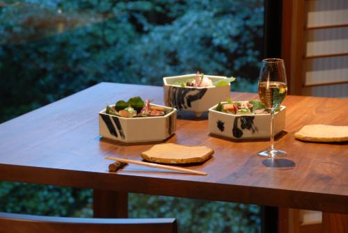 a table with two dishes of food and a glass of wine at Ryokan Sumiya Kihoan in Kameoka